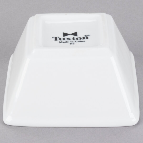 A bright white square Tuxton china bowl with black text reading "TuxTrendz Santorini" on the side.