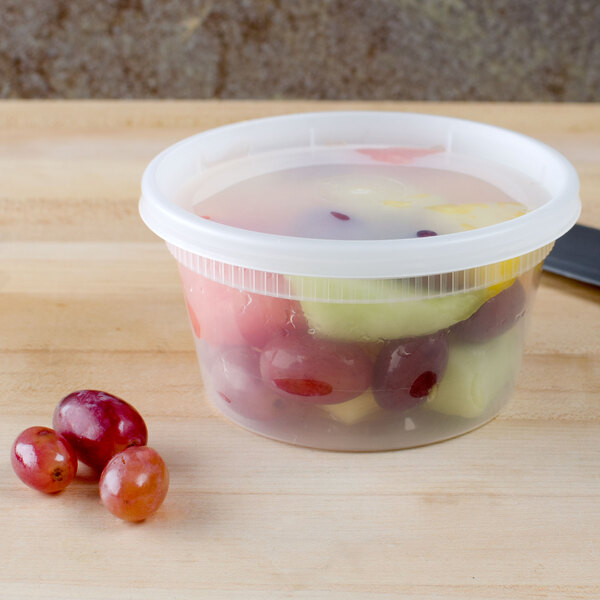 A Pactiv translucent plastic deli container filled with red and green grapes.