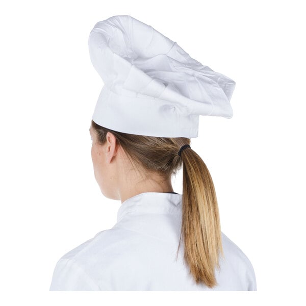 A person wearing a white chef's hat and white chef's coat, shown from the back.