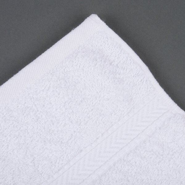 A white Oxford Gold Dobby hand towel on a gray surface.