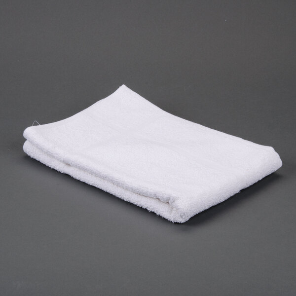A folded white Oxford Bronze bath mat on a gray surface.