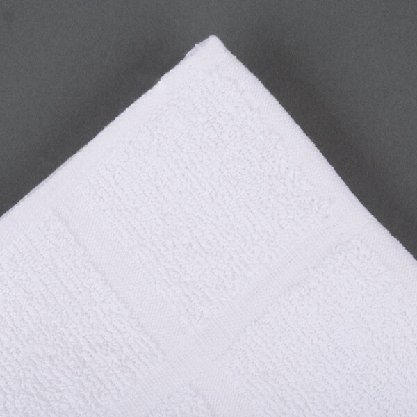 A white Oxford Bronze bath mat on a gray surface.