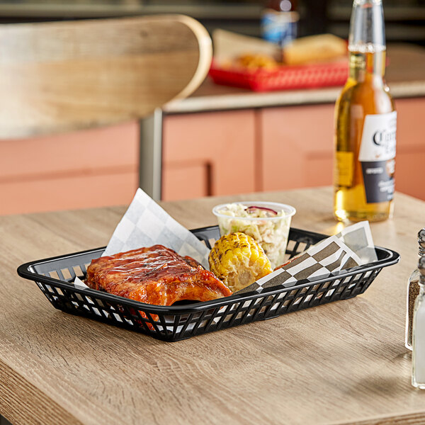 A Tablecraft black polypropylene rectangular fast food basket on a table with food in it.