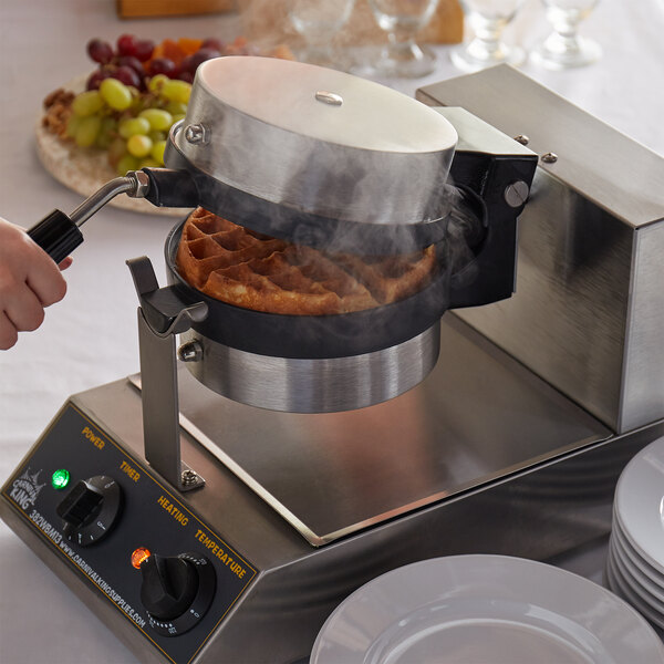 Hand opening steaming single waffle maker with cooked Belgian waffle inside