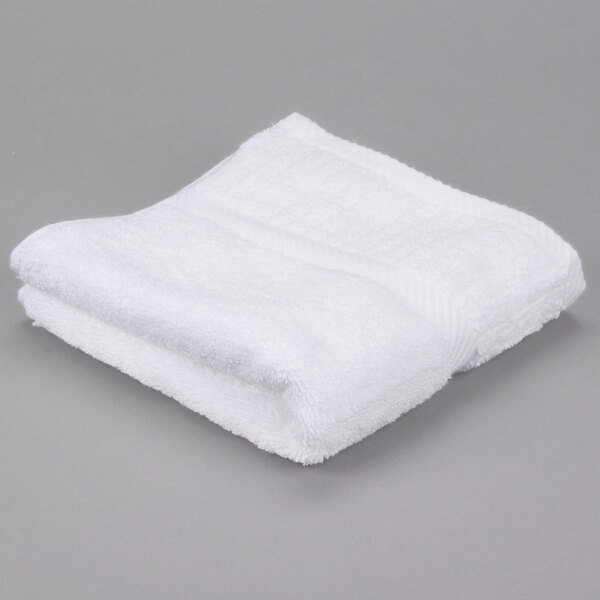 A folded white Oxford Signature hand towel on a gray surface.