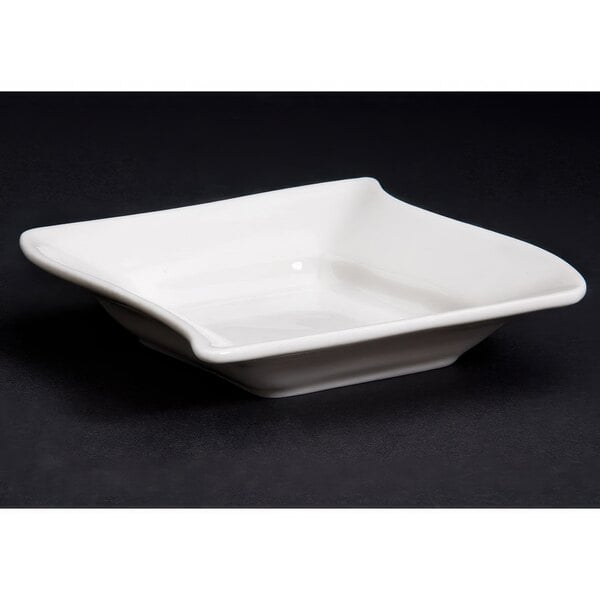 A CAC Soho ivory square stoneware monkey dish with a curved edge.