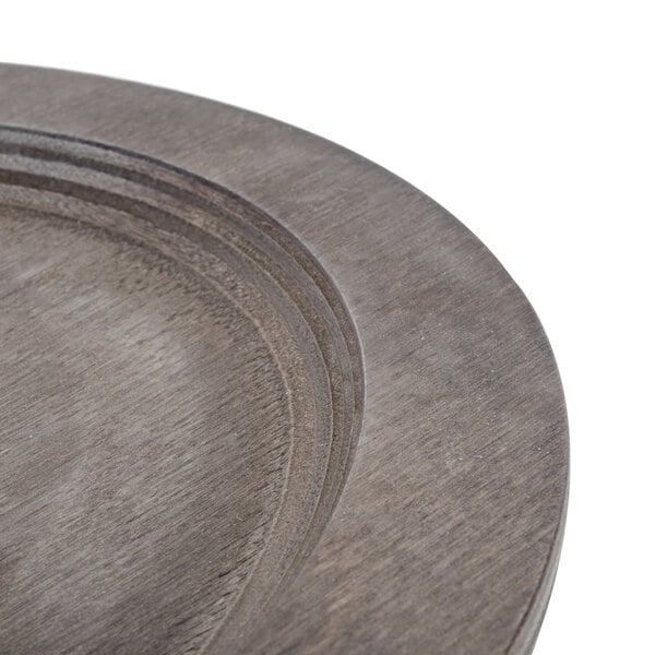 A Lodge oval wood underliner with a walnut finish on a table with a wood plate.