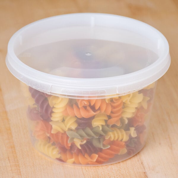 A translucent plastic round deli container filled with multicolored spiral pasta.
