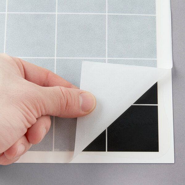 A hand holding a white Curtron insect trap glue board with a black grid.
