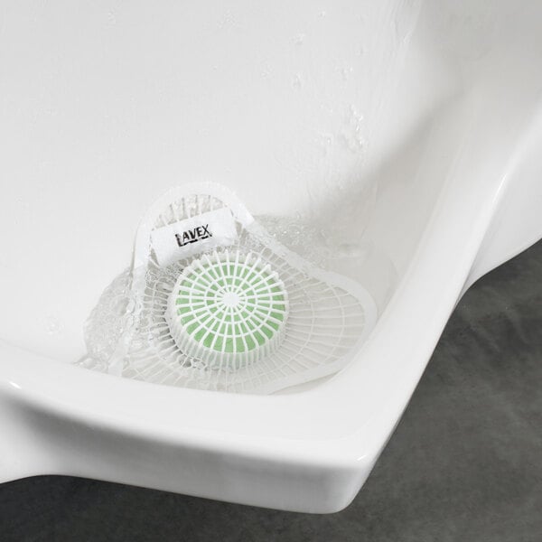 A white urinal with a green Lavex urinal screen in it.