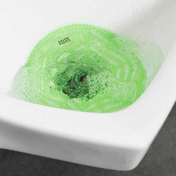 A Lavex Green Apple Scent deodorized gel urinal screen in a sink with green liquid and bubbles.