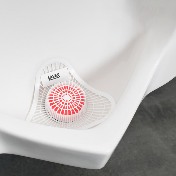 A white urinal with a red and white circular Lavex urinal screen in it.