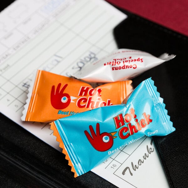 A group of small packets of Customizable Hard Cinnamon Balls on a black surface.