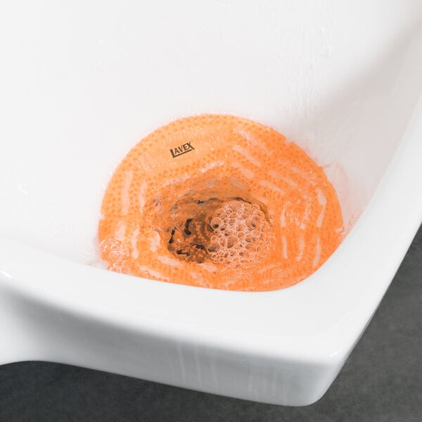 A white urinal with a Lavex citrus scented orange gel screen in it.