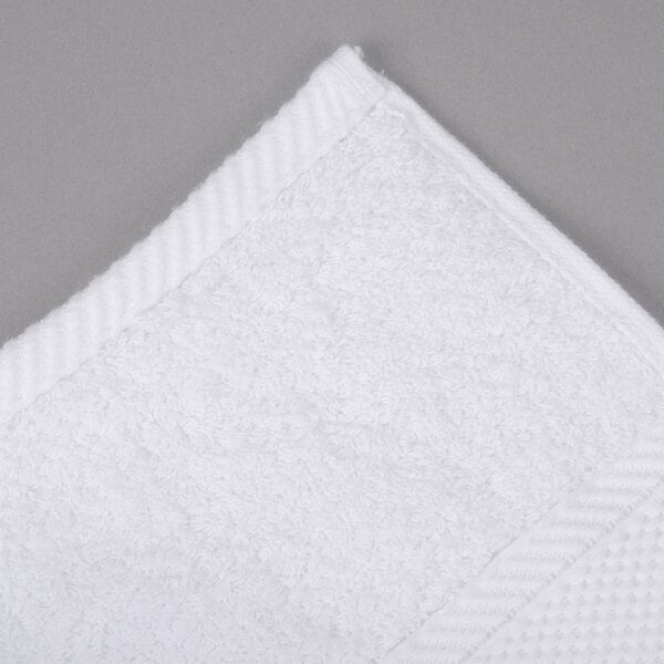 An Oxford Miasma white bath towel on a gray surface.