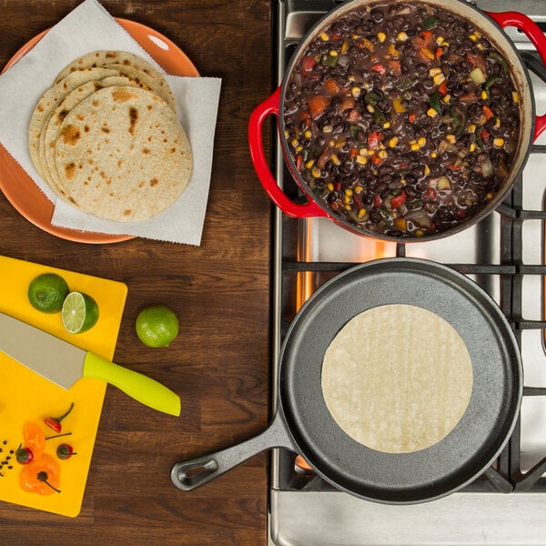 A Lodge cast iron griddle with a tortilla on it next to a pot of food.