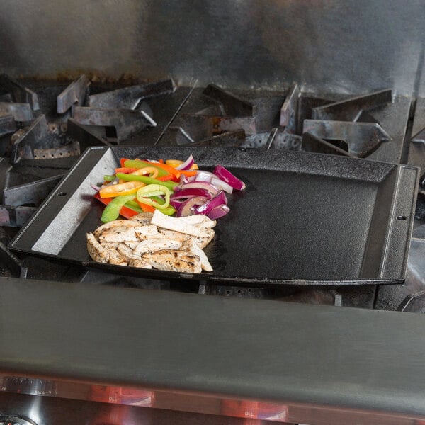 A Lodge rectangular cast iron fajita skillet with food on it.