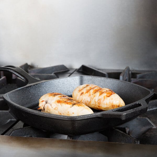 A Lodge cast iron square grill pan with two chicken breasts cooking in it.