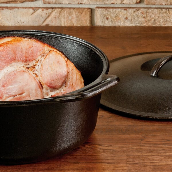 Cast iron dutch oven filled with ham, cover in the background