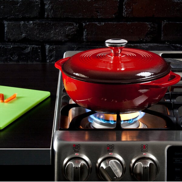 A Lodge Island Spice Red enameled cast iron dutch oven on a stove.