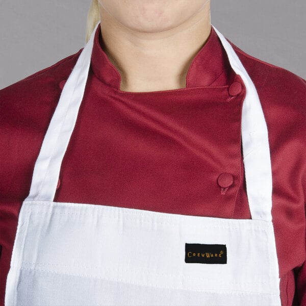 A woman wearing a white Chef Revival bib apron with a red shirt.