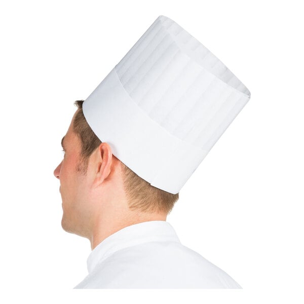 A person wearing a tall, white, pleated chef hat viewed from the side.