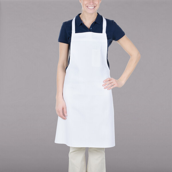 A woman wearing a white Chef Revival bib apron with one pocket.