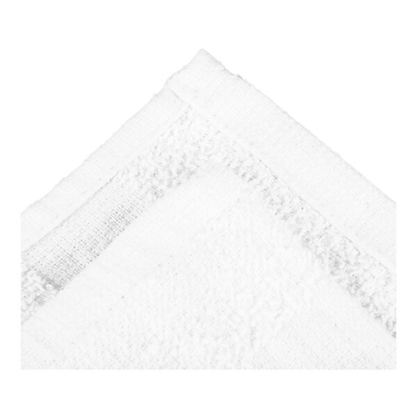 A close-up view of a white, textured fabric with a finished edge, likely a towel or cloth.