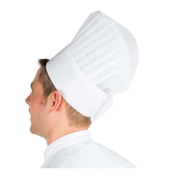 A person wearing a tall, white, pleated chef hat viewed from the side.