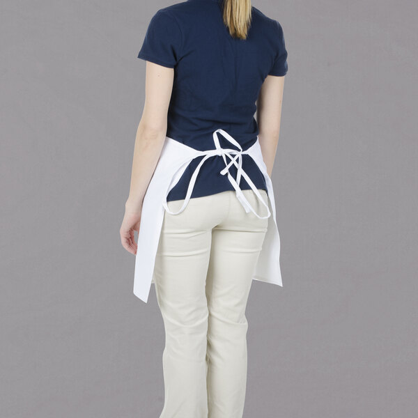 A woman wearing a Chef Revival white bistro apron with blue pants.