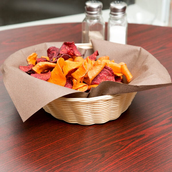 A natural rattan bread basket filled with chips on a table.