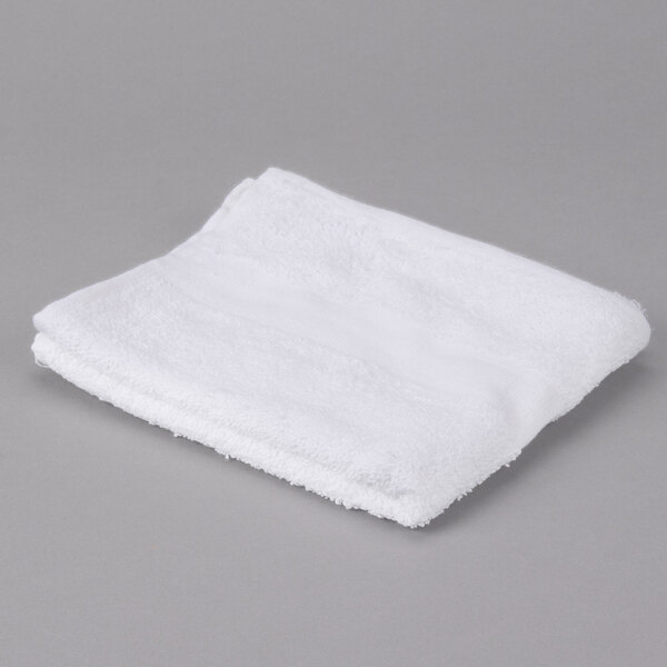 A folded white Oxford Gold hand towel with a cam border on a gray surface.