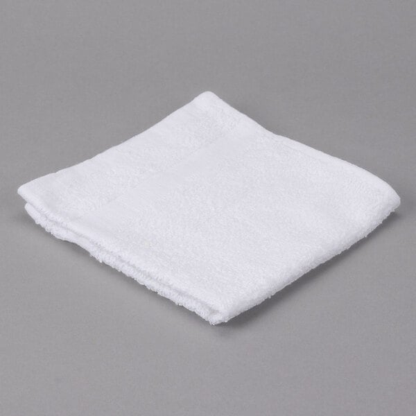 An Oxford Gold white cotton/poly wash cloth with a cam border on a gray surface.