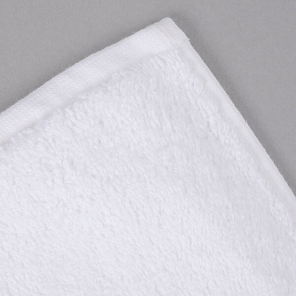A white Oxford Regale bath towel with a dobby border on a gray surface.
