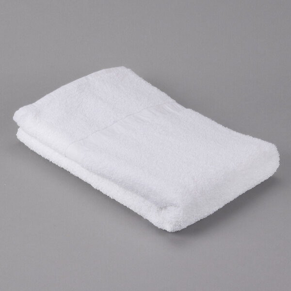 An Oxford Gold white bath towel with a cam border on a gray surface.