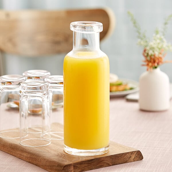 A Libbey Helio water bottle with orange liquid on a wooden board.