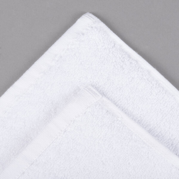 An Oxford Viceroy white terry towel bathmat with a checkered border and twill hem.