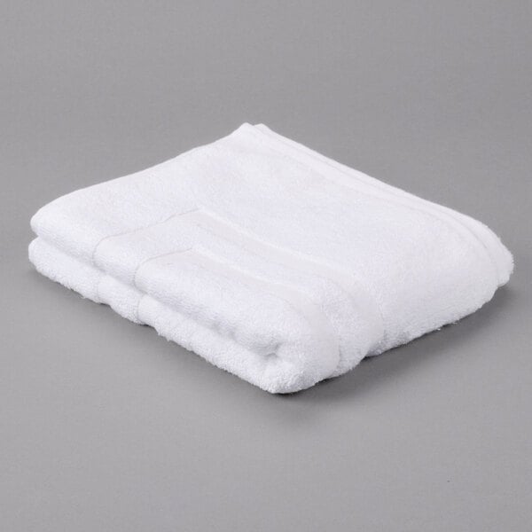 A folded white Oxford Regale bathmat on a gray surface.