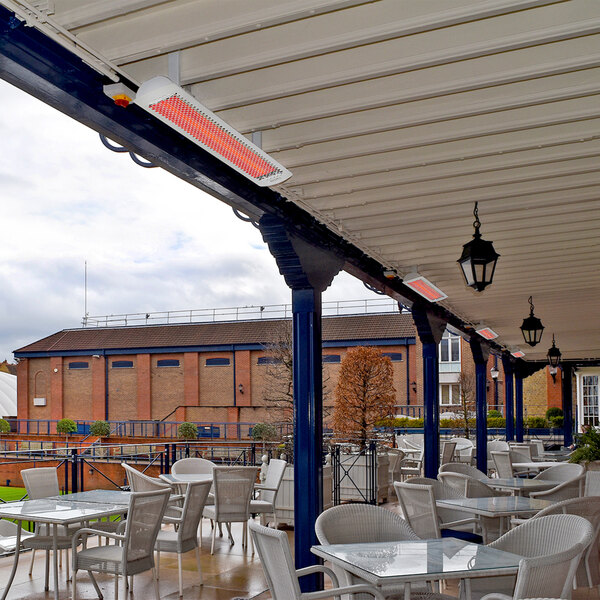 A white Bromic Heating Tungsten Smart-Heat electric patio heater on a patio with tables and chairs.