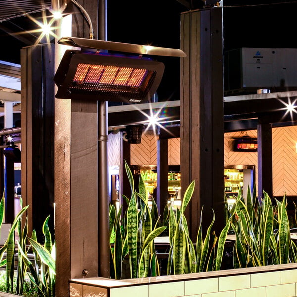 A wall-mounted propane outdoor patio heater with a protective grill and glowing heating elements.
