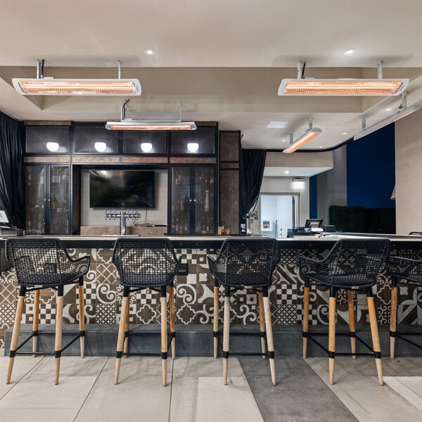 A white electric outdoor patio heater mounted on the ceiling above a bar area.
