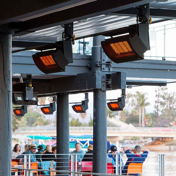 A group of people sitting on a deck with a Bromic Heating propane outdoor patio heater on a table.