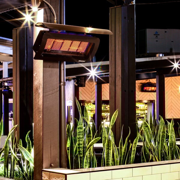 A wall-mounted natural gas outdoor patio heater with a protective grill and glowing heating elements.