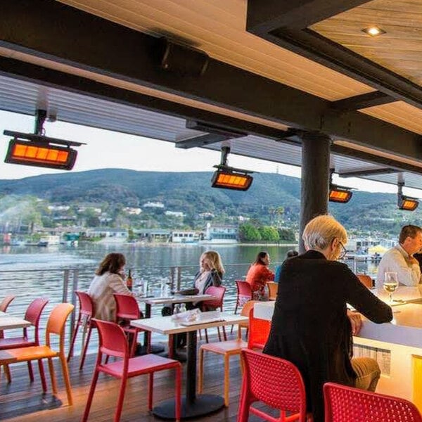 A natural gas outdoor patio heater mounted on the ceiling of a covered patio area overlooking a body of water.