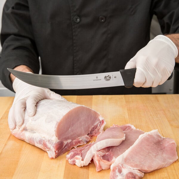 Chef using breaking knife to cut a large portion of meat