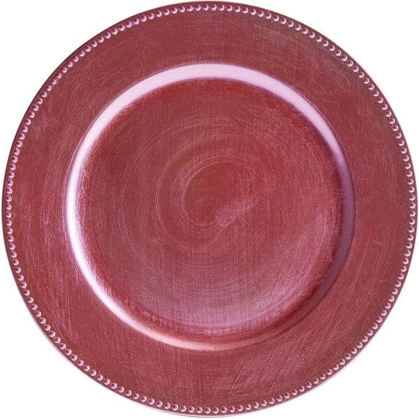 A pink plastic charger plate with a beaded edge.