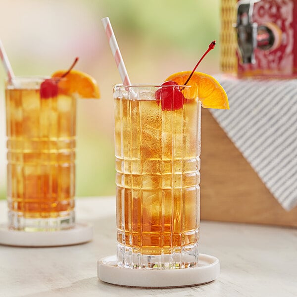 A table with two glasses of Bromley iced tea with ice, orange slices, and cherries.