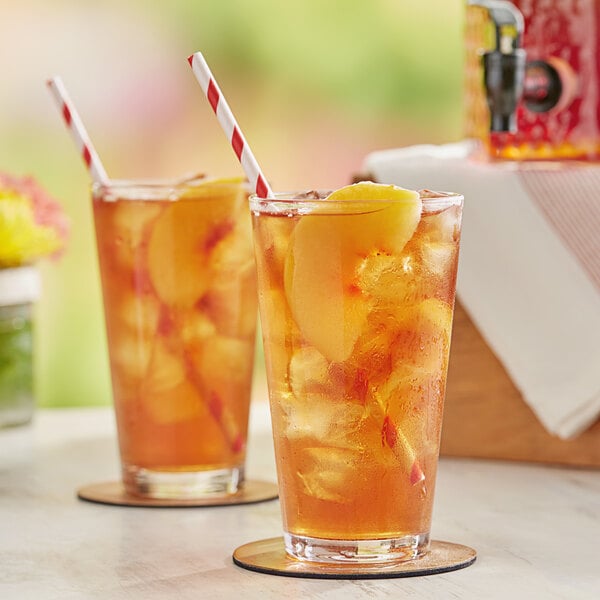 A couple of glasses of Bromley iced tea with lemons and straws on a table.