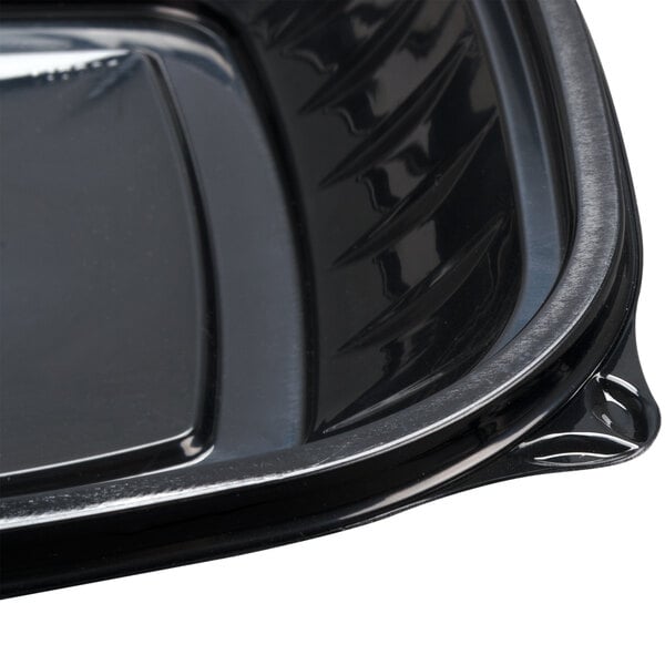 A Dart black plastic bowl with a lid on a table.