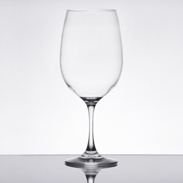 A clear plastic wine glass on a reflective surface.